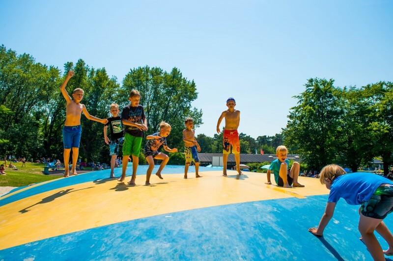 Kinder im Freibad hüfen auf Luftkissen