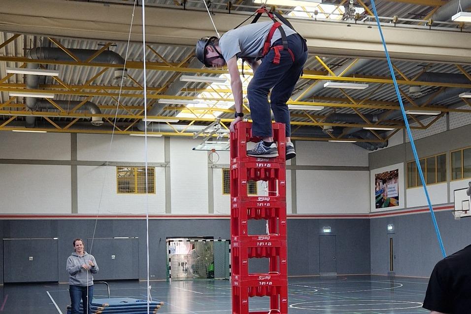 Kind kletter Kisten hoch, Betreuer sichert mit Seil