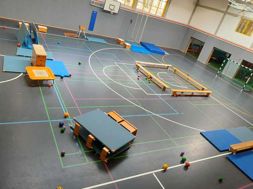 Geräteaufbau mit Matten, Springbock etc. in Sporthalle