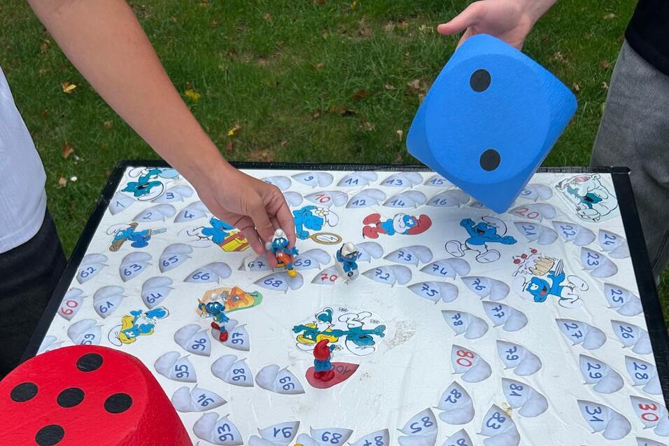 Chaosspiel in Schlumpfhausen Tisch mit Würfeln und Figuren des Chaosspiels