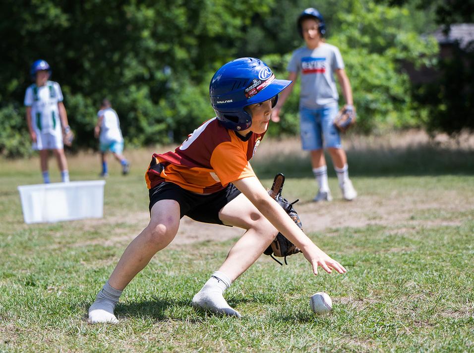 Baseball Fänger Kind mit Helm und Handschuh fängt den Ball