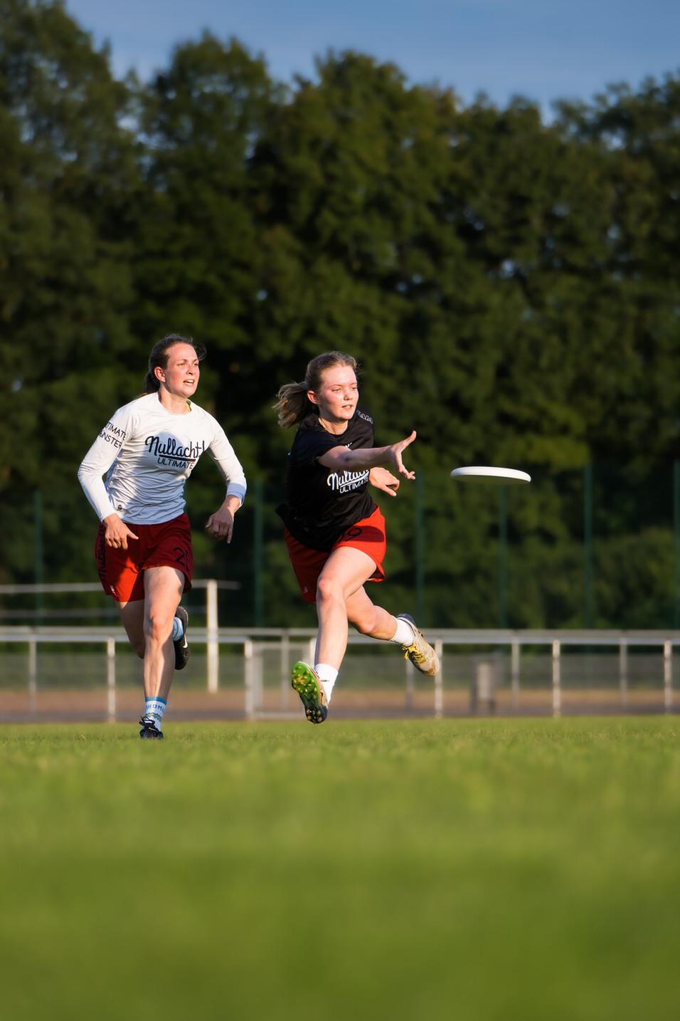 Zwei Mädchen spielen ultimate frisbee auf Wiese