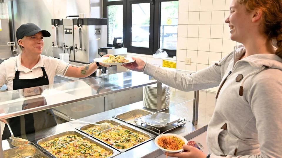 Frau gibt am Buffet Essen an Mädchen aus