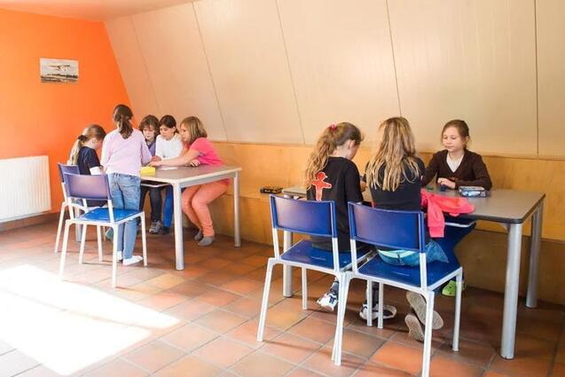 Mädchen sitzen im Gästehaus und spielen an Tischen