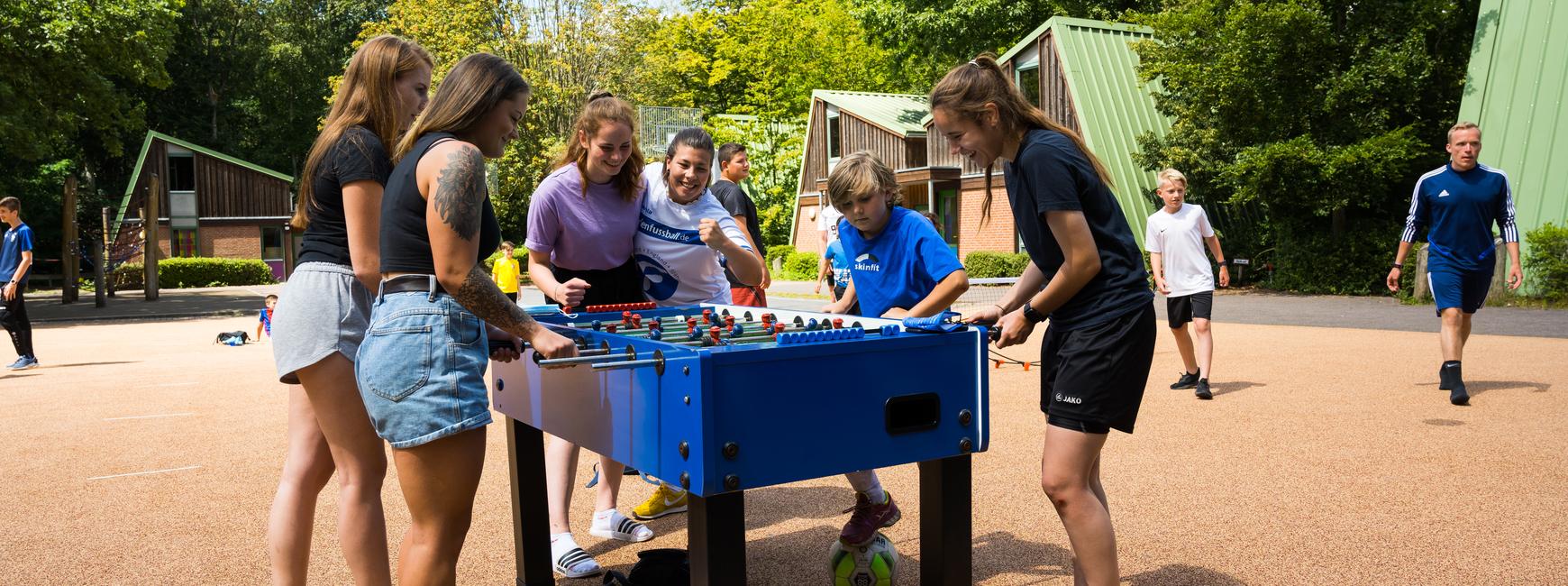Jugendliche spielen draußen am Kicker-Automat