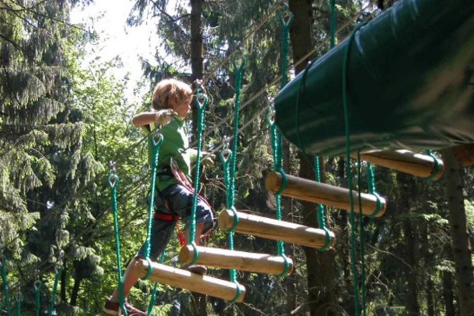 Kind läuft im Kletterwald über Hängebrücke