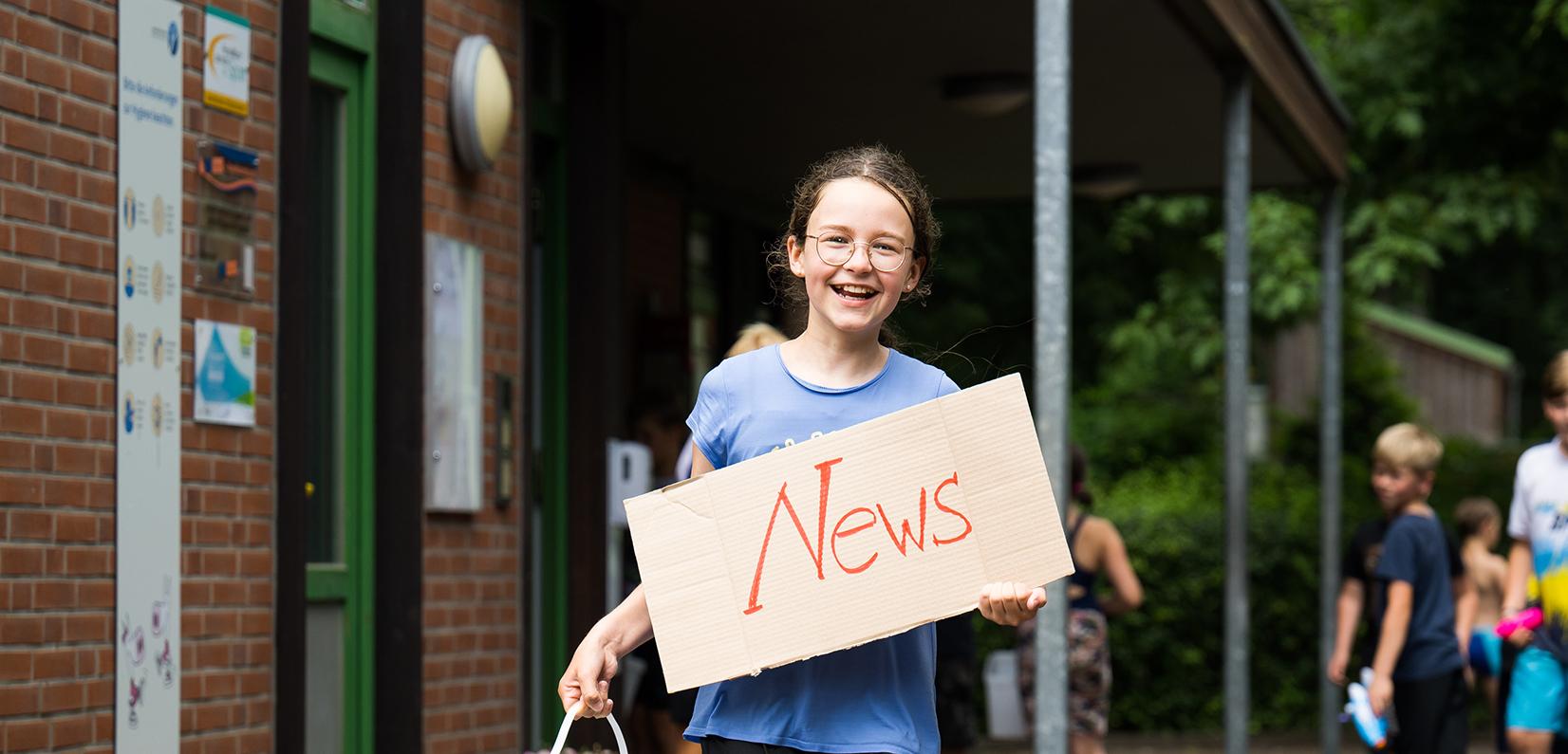 Mädchen hält Plakat in der Hand mit Aufschrift "News"