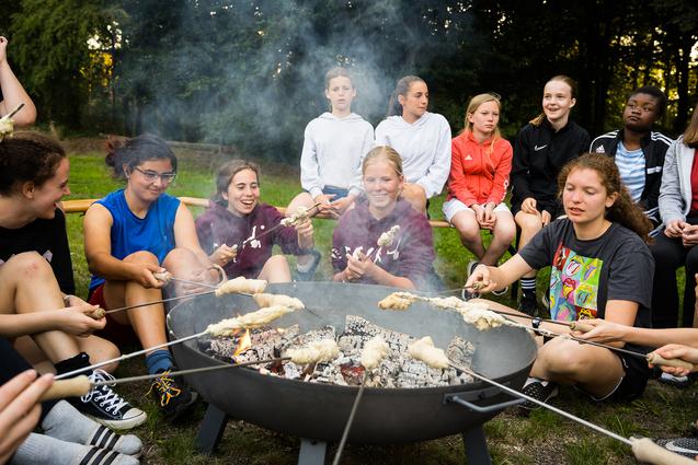 Jugendliche machen Stockbrot am Feuer