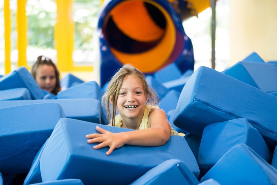 Mädchen spielt in mit Schaumstoffwürfeln gefüllter Grube im FlipHop