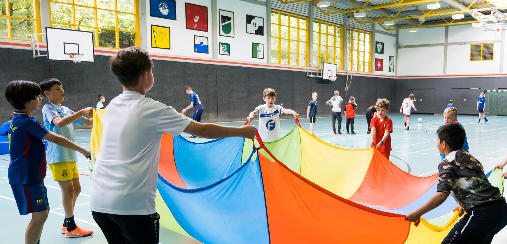 Kinder spielen mit Tuch in Sporthalle