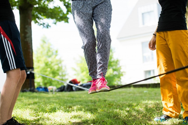 Eine Person aus Slackline, zwei halten fest