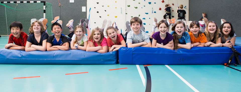 Kinder klettern in der Halle und liegen auf Matten